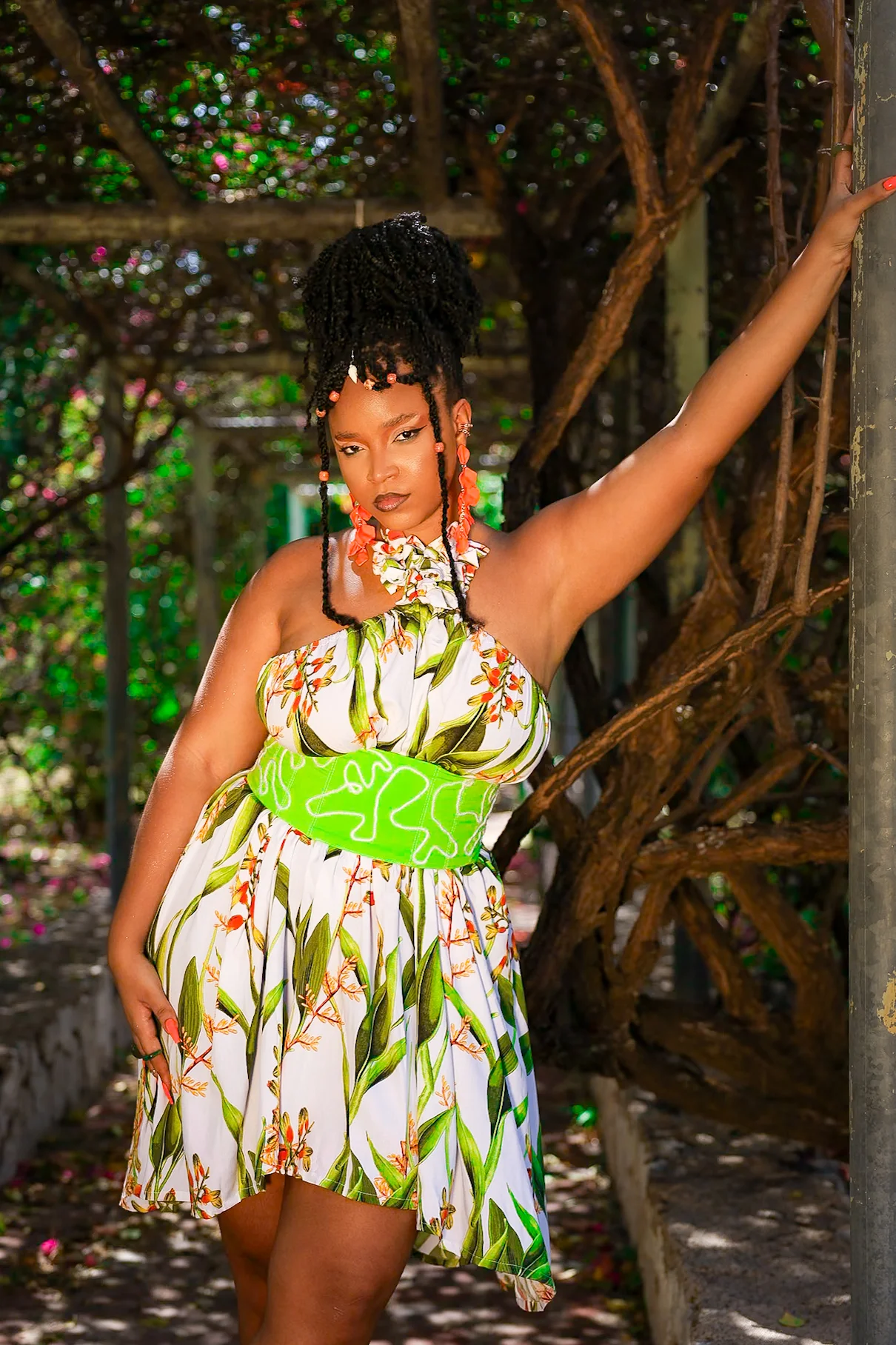 Woman in a floral dress posing beneath a garden arbor