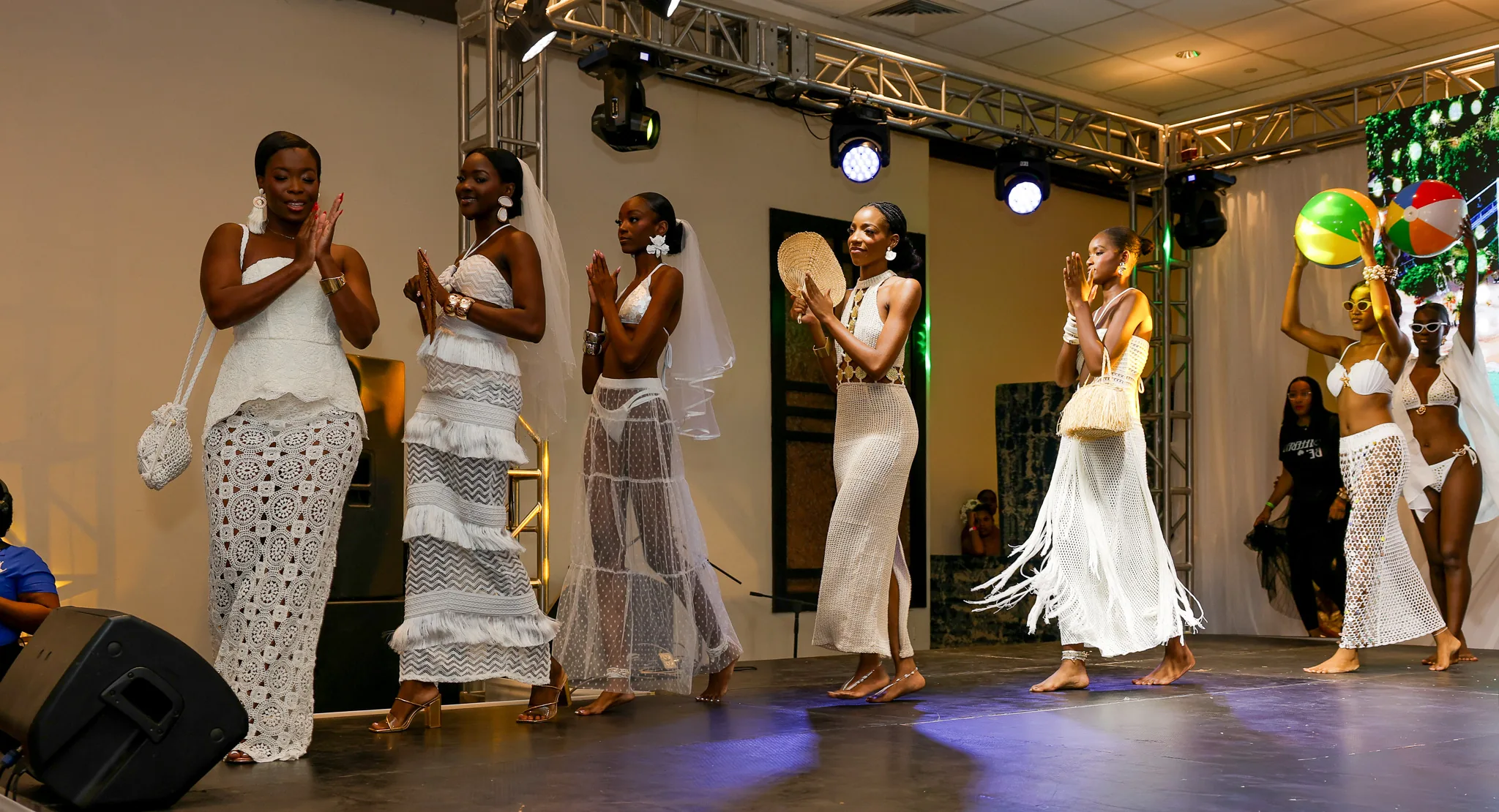 Models present a collection of white bridal looks on stage