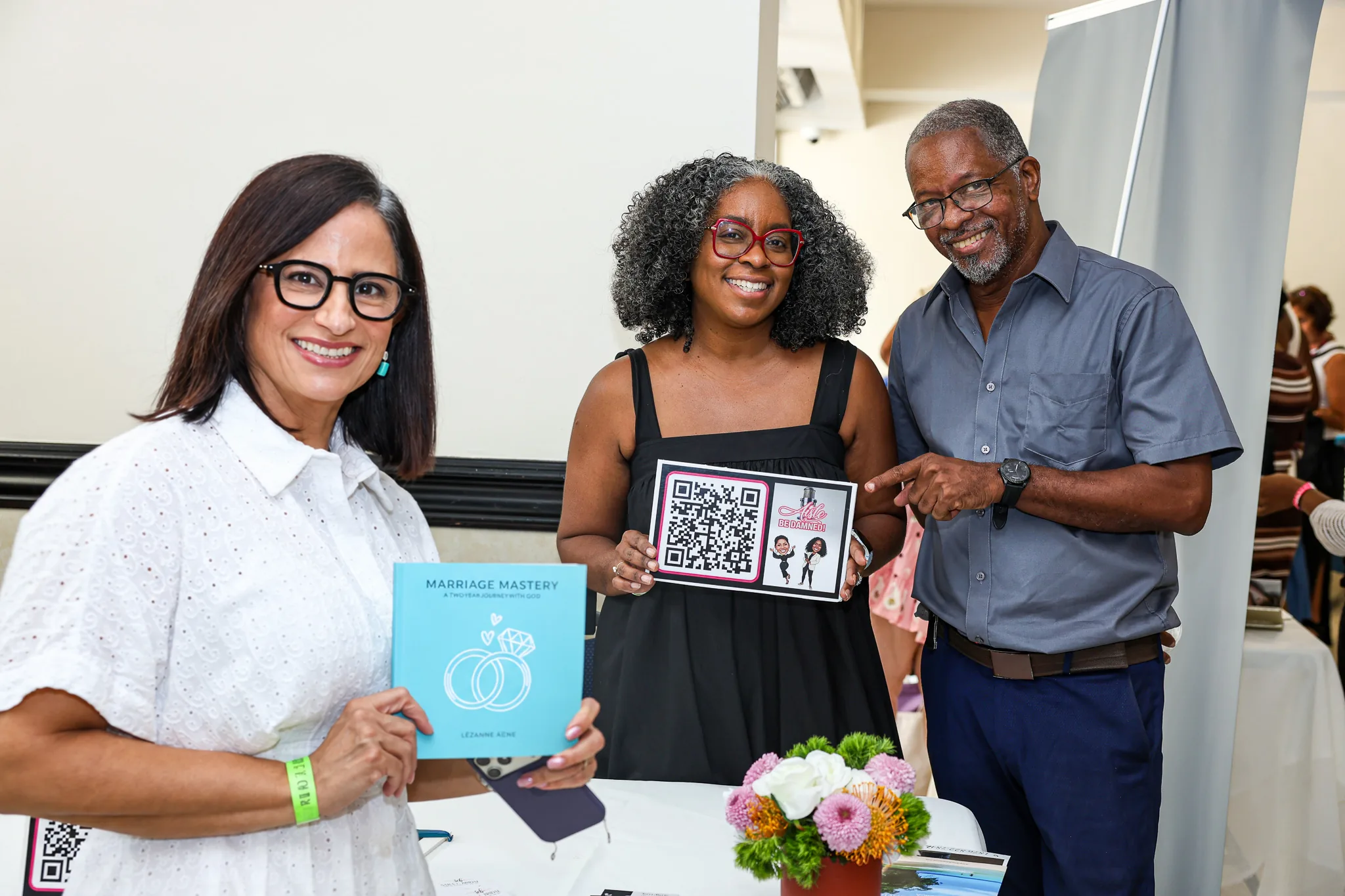 Three exhibitors share a smile at their booth