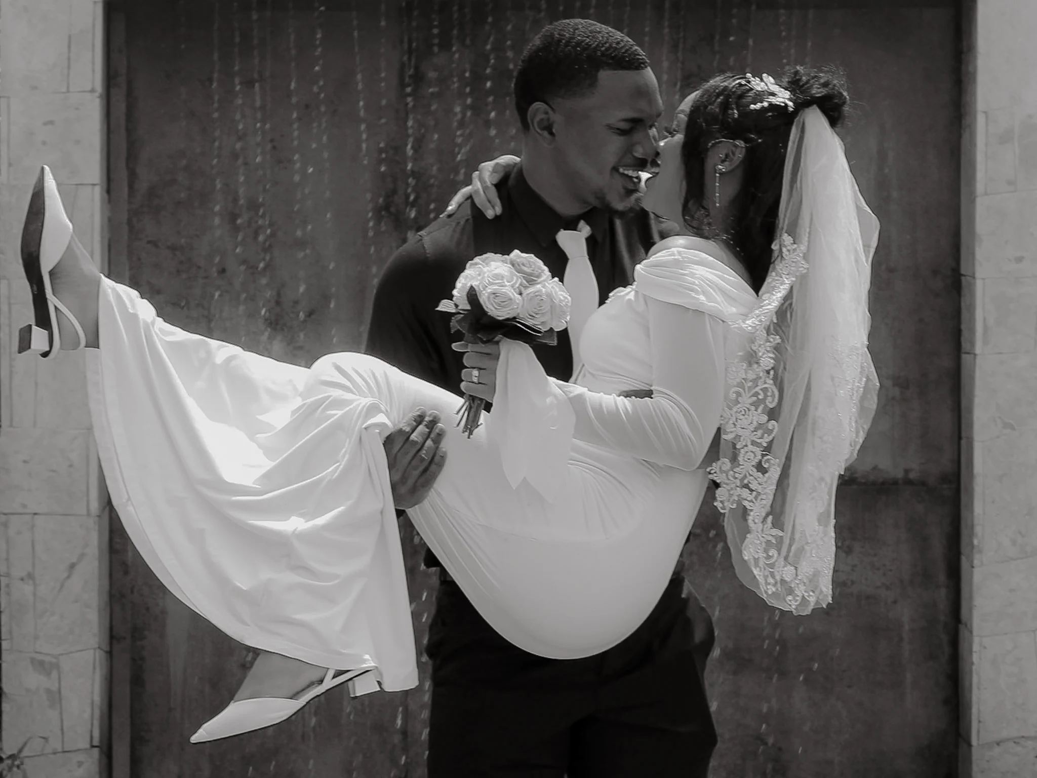 Black-and-white portrait of a groom carrying his bride